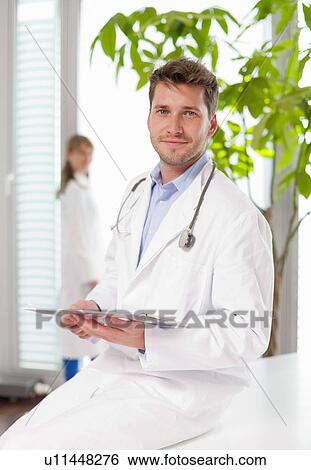 Doctor holding clipboard in hospital View Large Photo Image Stock Photograph - Doctor holding clipboard in hospital. Fotosearch