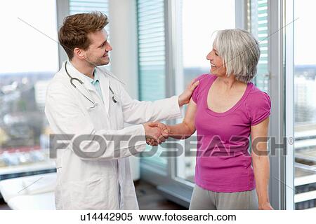 Stock Photography - Doctor shaking womans hand in office. Fotosearch