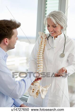 Doctor showing spine model to patient View Large Photo Image Stock Image - Doctor showing spine model to patient. Fotosearch