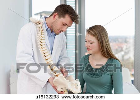 Stock Image - Doctor showing spine model to patient. Fotosearch