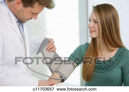 Doctor taking girls blood pressure View Large Photo Image Stock Photo - Doctor taking girls blood pressure. Fotosearch