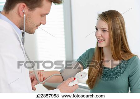Doctor taking girls blood pressure View Large Photo Image Stock Photo - Doctor taking girls blood pressure. Fotosearch