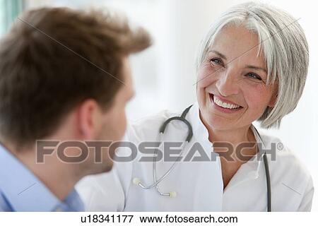 Doctor talking to man in office View Large Photo Image Stock Photo - Doctor talking to man in office. Fotosearch