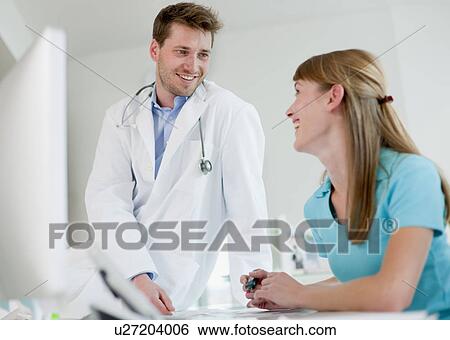 Doctor talking to receptionist in office View Large Photo Image Stock Photograph - Doctor talking to receptionist in office. Fotosearch