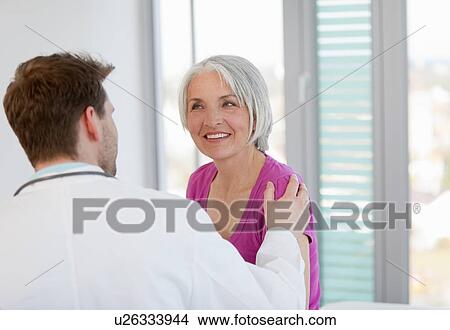 Doctor talking to woman in office View Large Photo Image Picture - Doctor talking to woman in office. Fotosearch