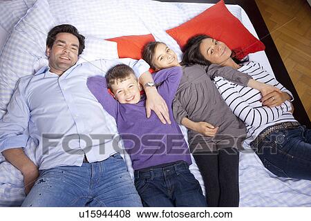 Family laying on bed together View Large Photo Image Stock Photo - Family laying on bed together. Fotosearch