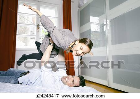Stock Photo - Father and daughter playing on bed. Fotosearch