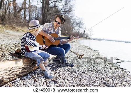 Father and son playing guitars by creek View Large Photo Image Stock Photo - Father and son playing guitars by creek. Fotosearch