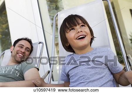 Stock Photo - Father and son relaxing in deck chairs. Fotosearch