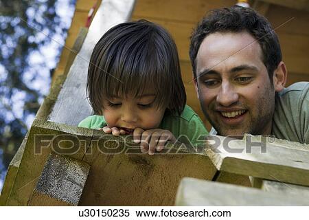 Stock Photography - Father and son sitting in tree house. Fotosearch