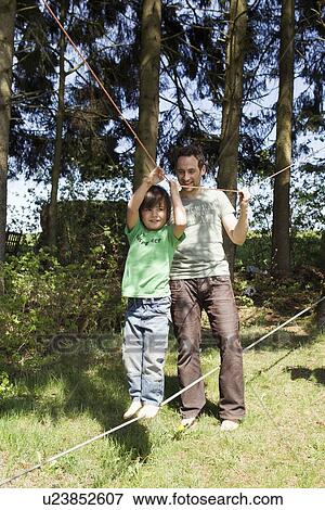 Father helping son walk on tight rope View Large Photo Image Stock Photo - Father helping son walk on tight rope. Fotosearch