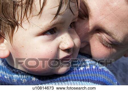 Stock Image - Father kissing sons cheek. Fotosearch