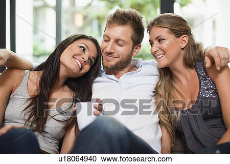 Stock Image - Friends having coffee together on sofa. Fotosearch