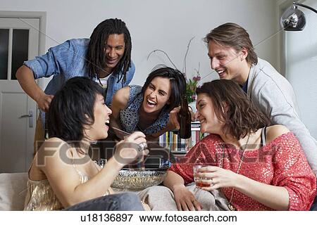 Friends laughing together in living room View Large Photo Image Stock Photo - Friends laughing together in living room. Fotosearch