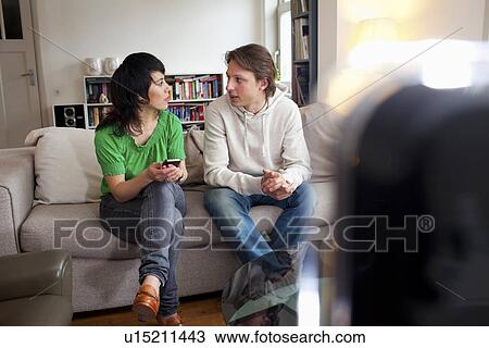 Friends relaxing together in living room View Large Photo Image Stock Image - Friends relaxing together in living room. Fotosearch