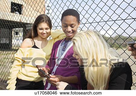 Stock Photograph - Friends using cell phone on city street. Fotosearch