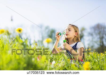 Girl blowing bubbles in field View Large Photo Image Stock Image - Girl blowing bubbles in field. Fotosearch