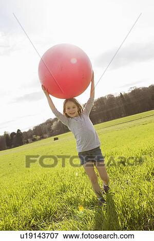 Girl carrying bouncy ball in field View Large Photo Image Stock Photo - Girl carrying bouncy ball in field. Fotosearch