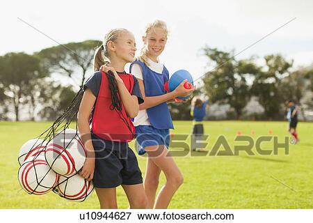Girl carrying soccer balls on pitch View Large Photo Image Stock Photo - Girl carrying soccer balls on pitch. Fotosearch