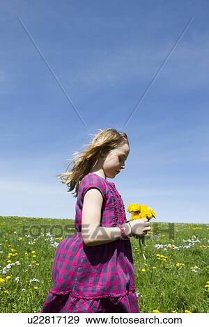 Stock Photo - Girl carrying wildflowers in field. Fotosearch