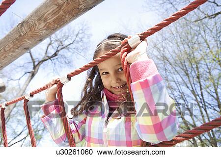 Stock Image - Girl climbing ropes in playground. Fotosearch