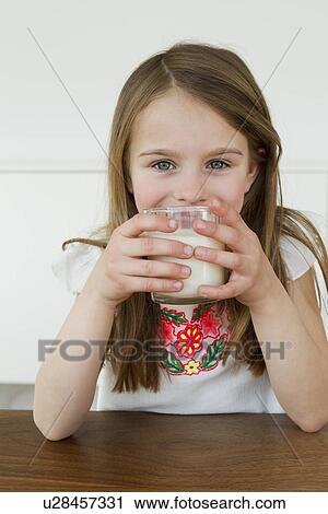 Girl drinking glass of milk at table View Large Photo Image Stock Image - Girl drinking glass of milk at table. Fotosearch