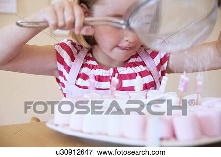 Stock Photo - Girl dusting candies with sugar. Fotosearch