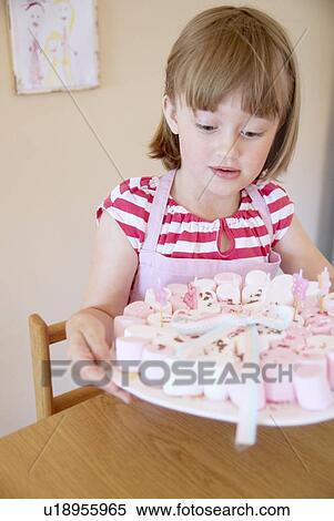 Stock Photography - Girl holding tray of candies in kitchen. Fotosearch