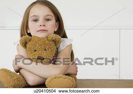 Girl hugging teddy bear at table View Large Photo Image Picture - Girl hugging teddy bear at table. Fotosearch