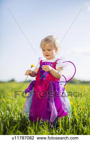Stock Image - Girl in fairy costume playing in field. Fotosearch