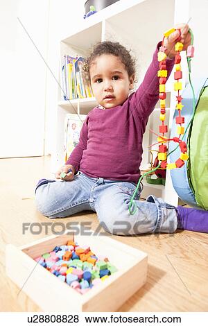Girl playing with string of wooden beads View Large Photo Image Stock Photo - Girl playing with string of wooden beads. Fotosearch