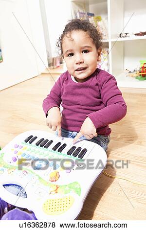 Stock Photo - Girl playing with toy piano. Fotosearch