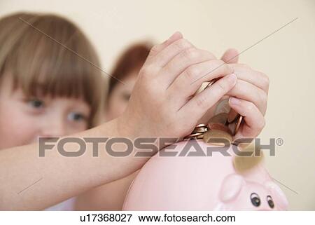 Girl putting money in piggy bank View Large Photo Image Stock Photo - Girl putting money in piggy bank. Fotosearch