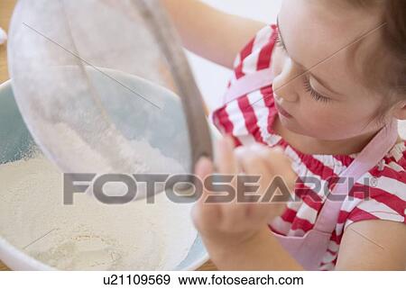 Girl sifting flour in kitchen View Large Photo Image Stock Photo - Girl sifting flour in kitchen. Fotosearch