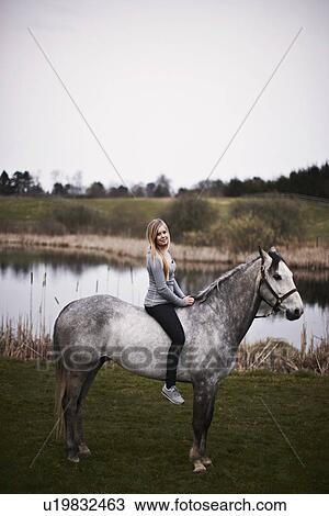 Girl sitting on horse in field View Large Photo Image Stock Image - Girl sitting on horse in field. Fotosearch