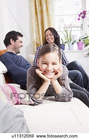 Girl smiling on sofa in living room View Large Photo Image Stock Photo - Girl smiling on sofa in living room. Fotosearch