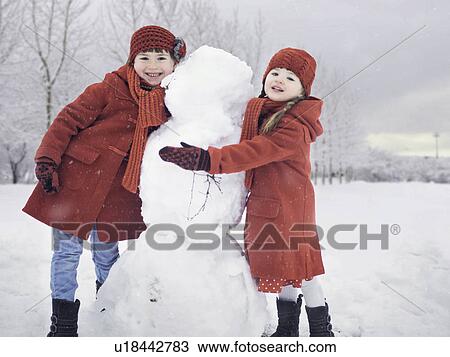 Girls building snowman outdoors View Large Photo Image Stock Image - Girls building snowman outdoors. Fotosearch