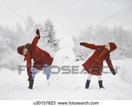 Girls building snowman outdoors View Large Photo Image Stock Image - Girls building snowman outdoors. Fotosearch