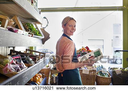 Stock Image - Grocer arranging produce for sale. Fotosearch
