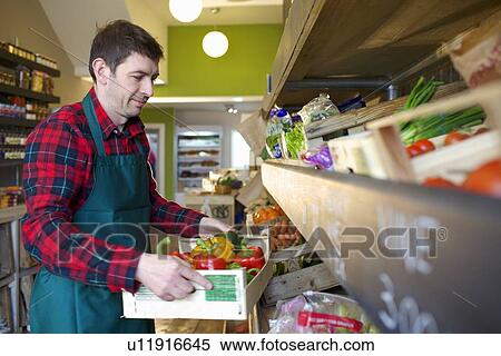 Stock Photography - Grocer arranging produce for sale. Fotosearch