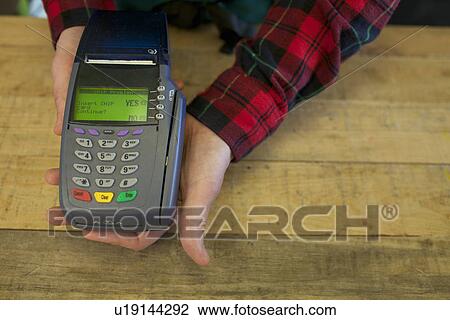 Grocer holding credit card machine View Large Photo Image Stock Image - Grocer holding credit card machine. Fotosearch