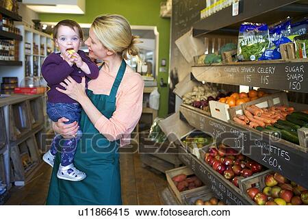 Grocer holding daughter in store View Large Photo Image Stock Photography - Grocer holding daughter in store. Fotosearch