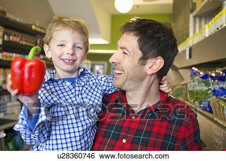 Grocer holding son with bell pepper View Large Photo Image Stock Photograph - Grocer holding son with bell pepper. Fotosearch
