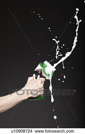 Picture - Hand squeezing carton of milk. Fotosearch
