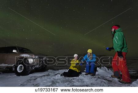 Stock Photo - Hikers relaxing under aurora borealis. Fotosearch