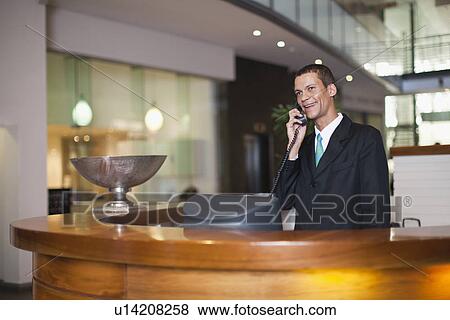 Hotel concierge talking on phone View Large Photo Image Stock Photo - Hotel concierge talking on phone. Fotosearch