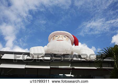 Stock Image - Inflatable Santa Claus over building. Fotosearch