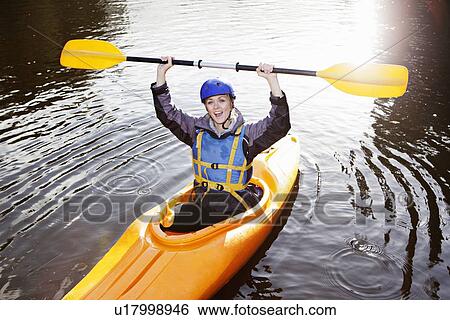 Stock Photograph - Kayaker holding oar in still lake. Fotosearch