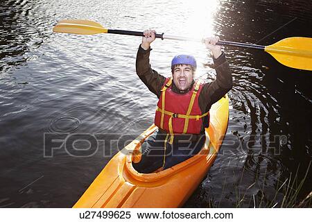 Stock Photography - Kayaker holding oar in still lake. Fotosearch