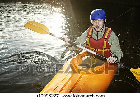Stock Photo - Kayaker rowing in still lake. Fotosearch
